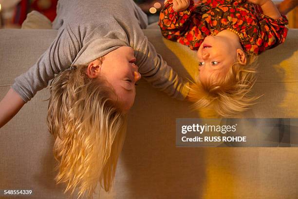 sisters lying over back of sofa - lying on back girl on the sofa stock-fotos und bilder