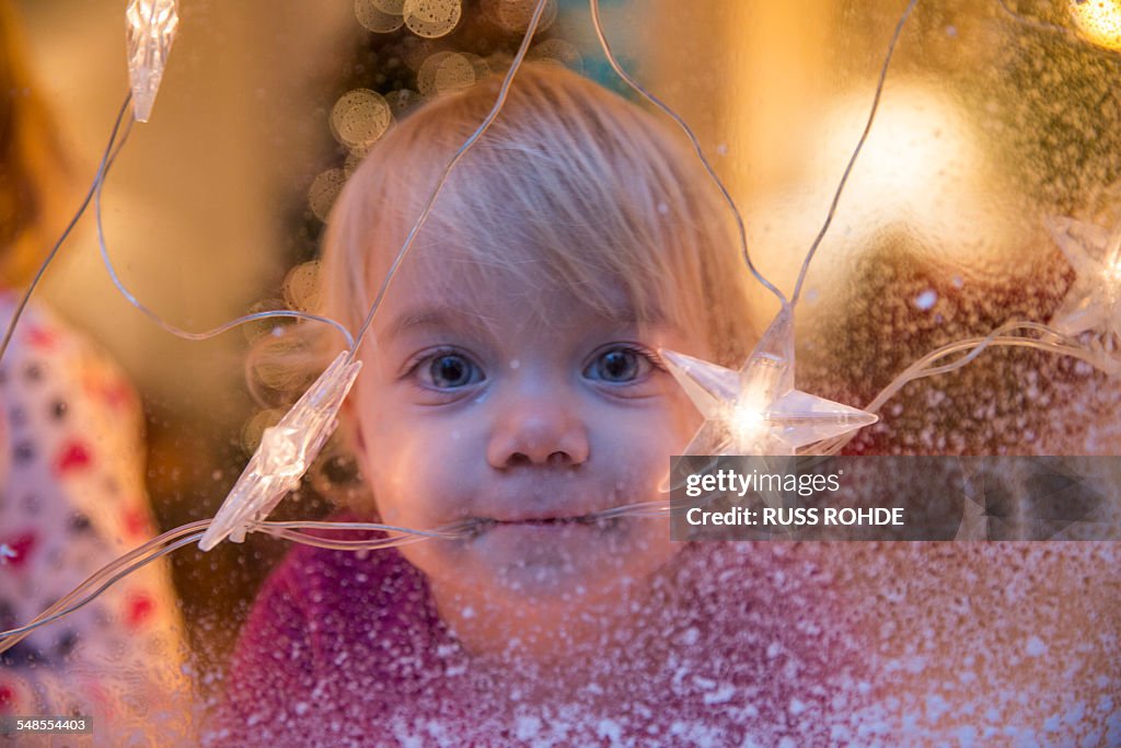 Sisters looking out of window with Christmas decorations