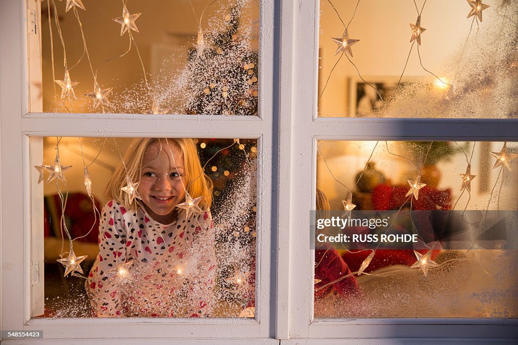 Girl looking out of window with Christmas decorations