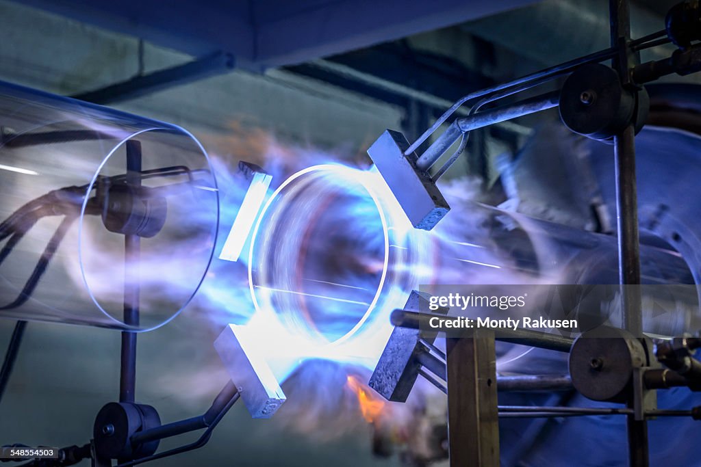 Large glass tube on lathe in glass factory