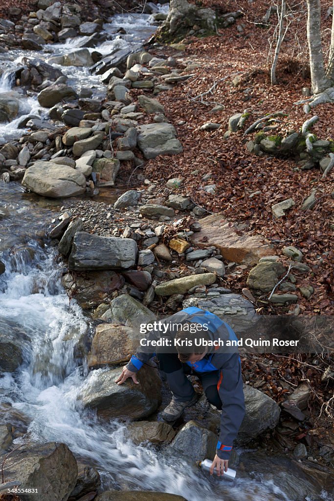 Hiker taking break by stream, Montseny, Barcelona, Catalonia, Spain