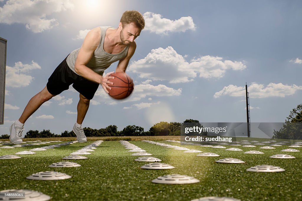 Young male basketball player doing push ups with ball on sports field