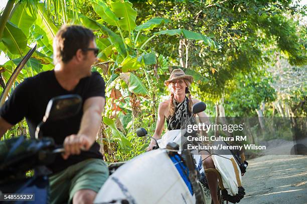 couple riding on motorbikes with surfboards, nusa lembongan, indonesia - motorcycle travel stock pictures, royalty-free photos & images