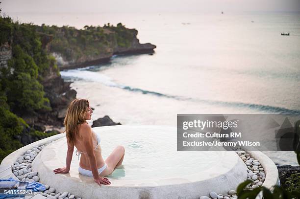 woman sitting in spa pool, looking out to sea, balangan, bali, indonesia - bali spa stock pictures, royalty-free photos & images