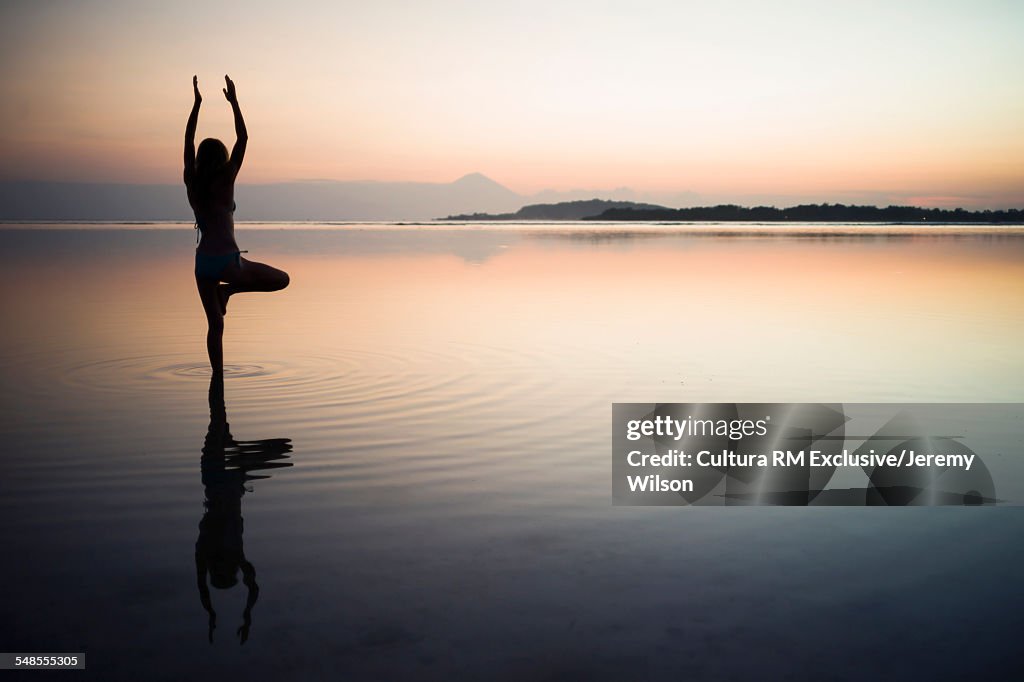 Woman in the sea, in yoga position, rear view, Gili Air, Indonesia