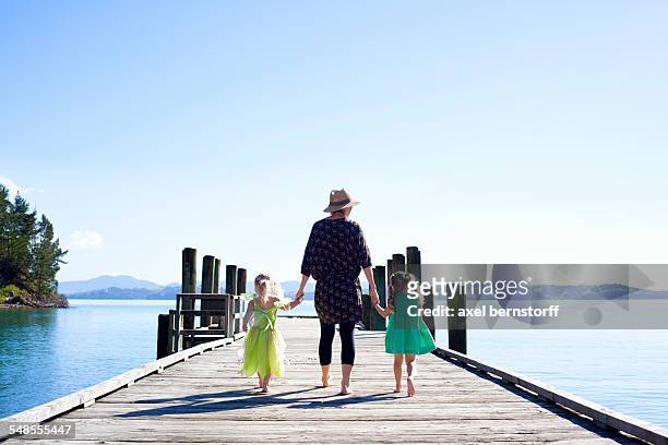 mid adult woman and daughters strolling on pier, new zealand - family new zealand stock-fotos und bilder