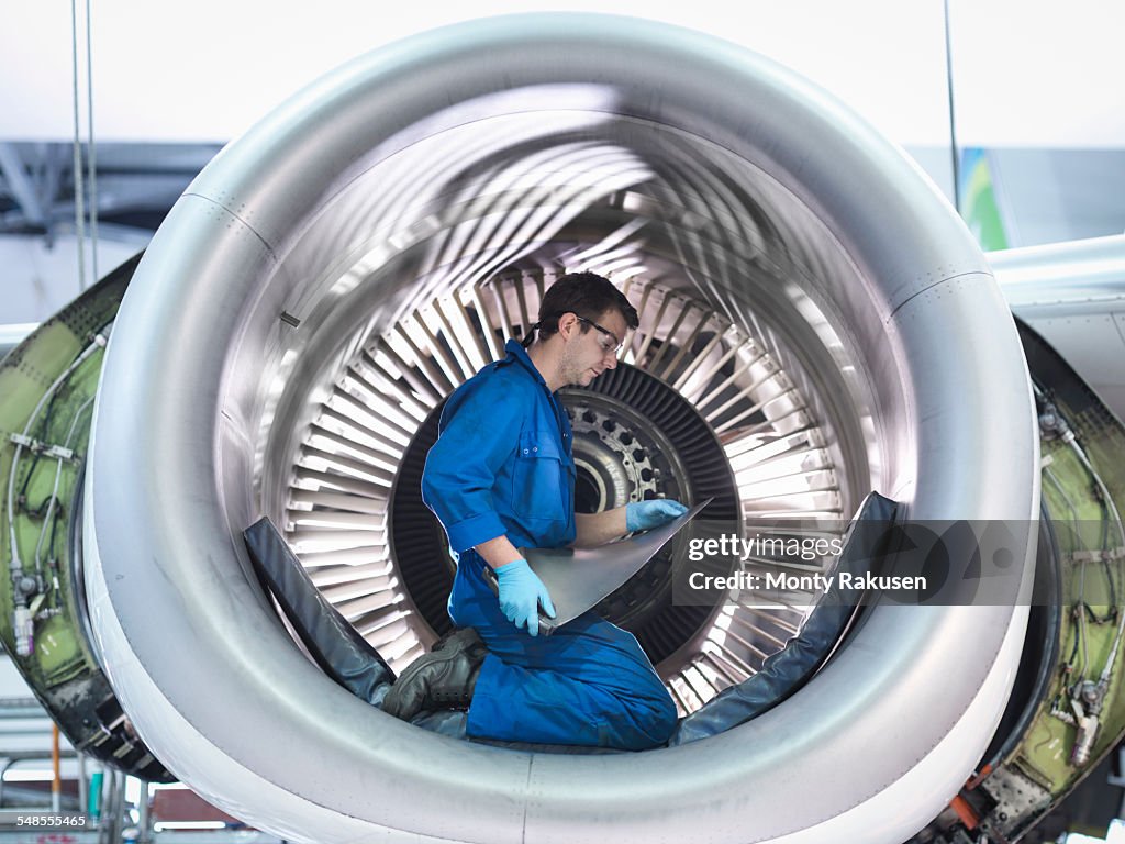 Engineer holding jet engine turbine blade in aircraft maintenance factory