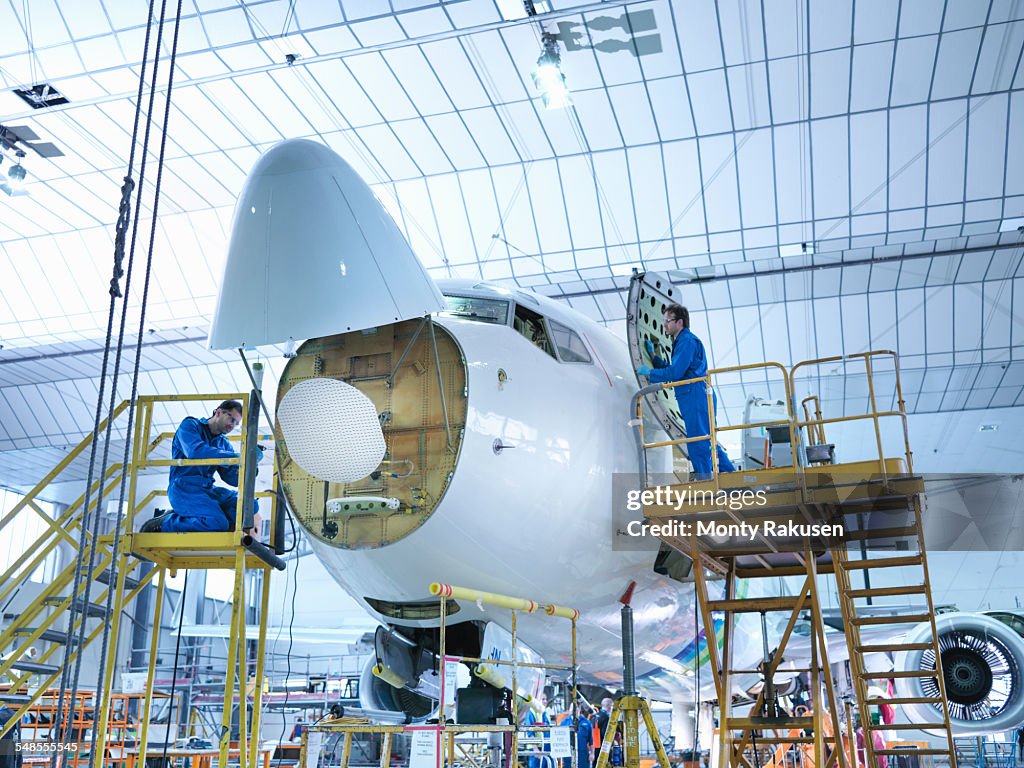 Engineers working on aircraft in aircraft maintenance factory