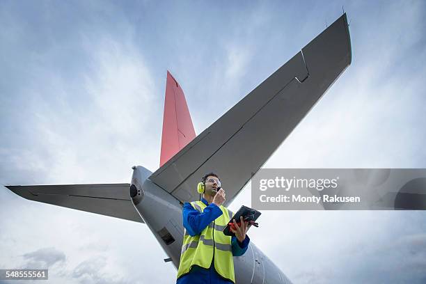 airside engineer talking on radio near aircraft on runway, low angle view - aviation worker stock pictures, royalty-free photos & images