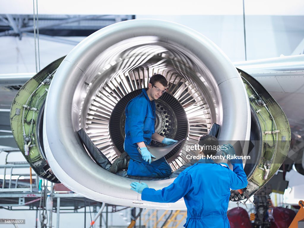 Engineers working with jet engine turbine blade in aircraft maintenance factory