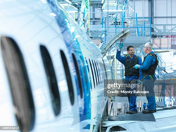 engineers in discussion on aircraft wing in aircraft maintenance factory - aerospace engineer ストックフォトと画像
