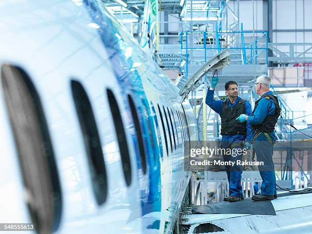 engineers in discussion on aircraft wing in aircraft maintenance factory - aviation engineering imagens e fotografias de stock