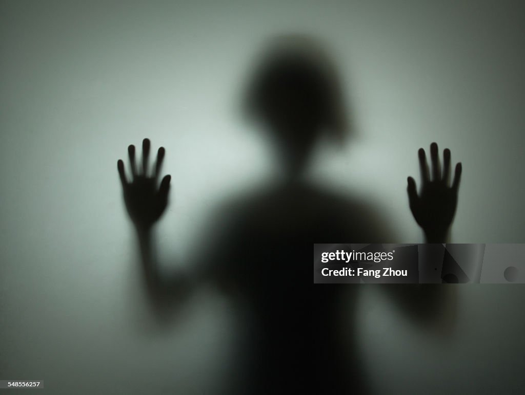 Silhouette of person behind glass