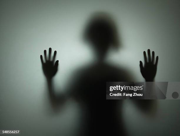 silhouette of person behind glass - sad business stock pictures, royalty-free photos & images