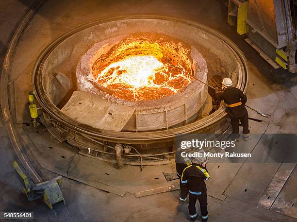 steel workers inspecting molten steel in flask, high angle view - fließend stock-fotos und bilder