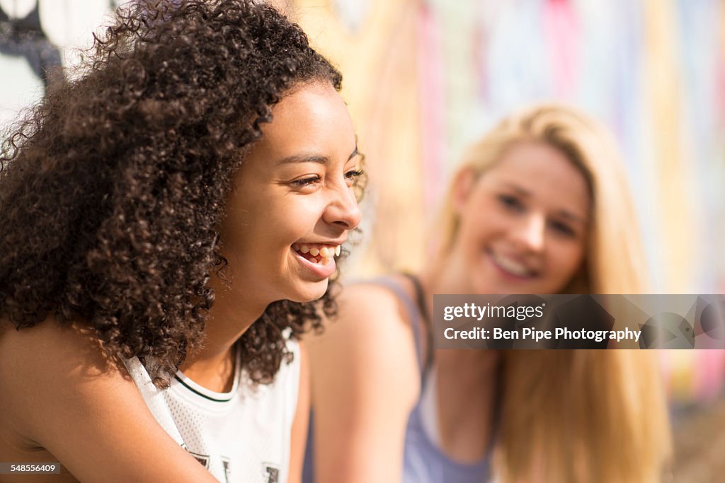 Teenagers relaxing against wall with graffiti