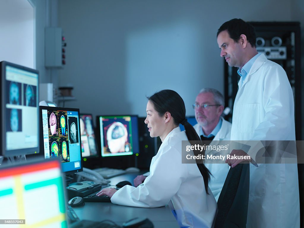 Doctors and scientists looking at screens of Magnetic Resonance Imaging (MRI) 3 Tesla twin speed scanner