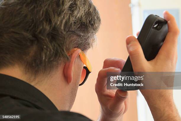 man with congenital blindness using assistive listening to hear his text messages - blind man stock pictures, royalty-free photos & images