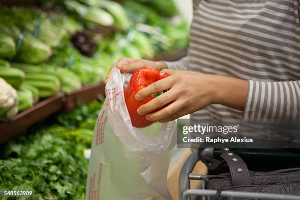 cropped shot of young woman selecting red pepper at health food store - plastic bag stock-fotos und bilder