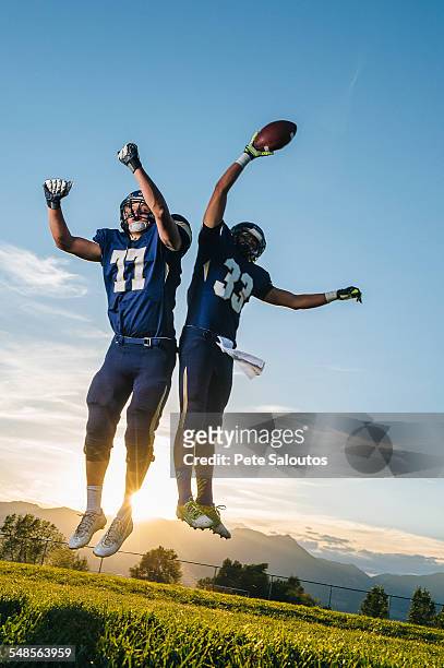 two teenage american football players jumping for ball - yankees spring training stock pictures, royalty-free photos & images