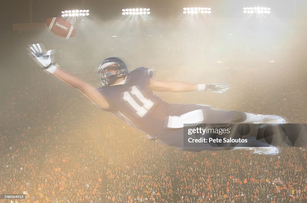 Teenage American football player jumping and reaching for ball