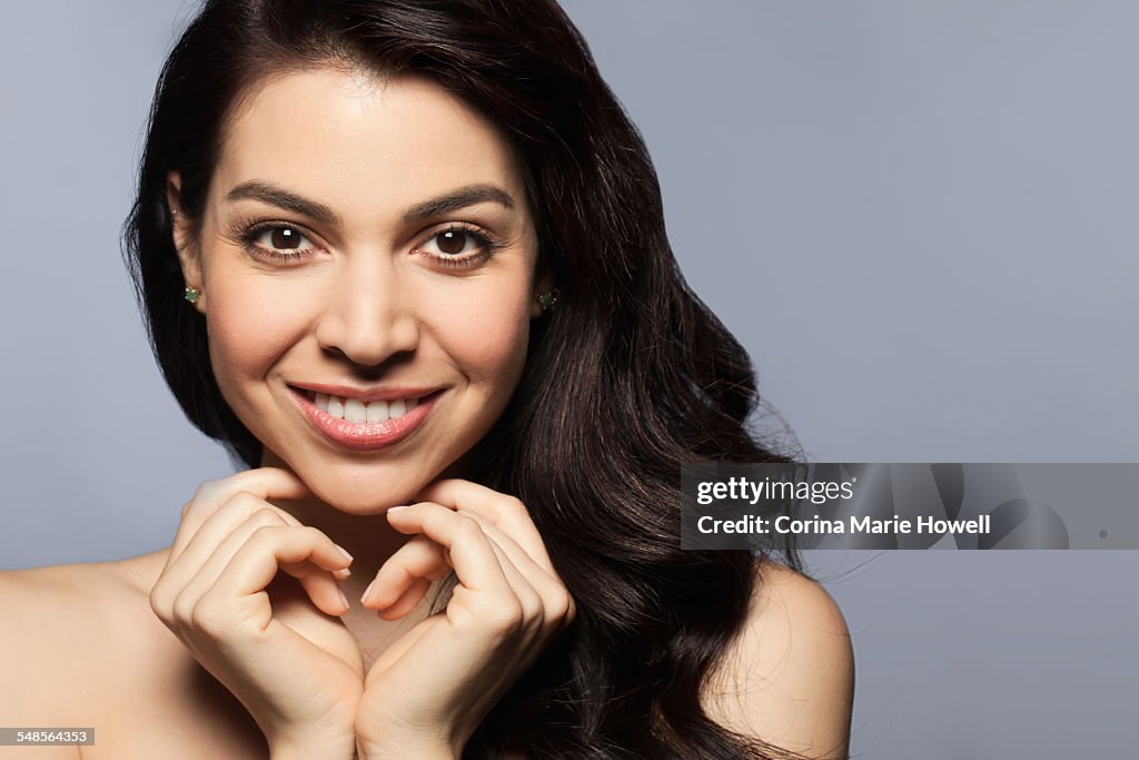 Mid adult woman with hands touching chin, smiling