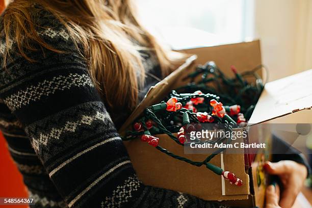 woman carrying christmas lights in cardboard box - christmas decorations stock pictures, royalty-free photos & images