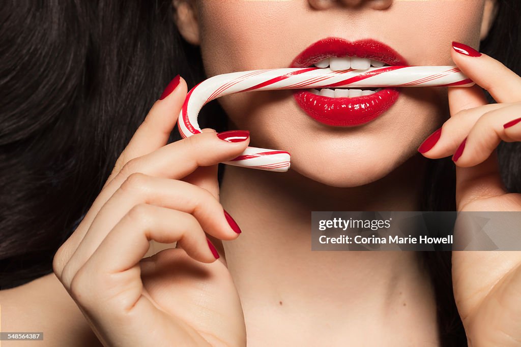 Mid adult woman biting candy cane