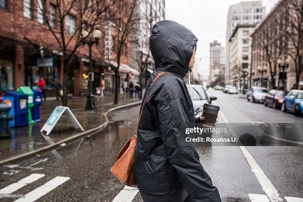 Young woman on rainy pedestrian crossing, Seattle, Washington State, USA