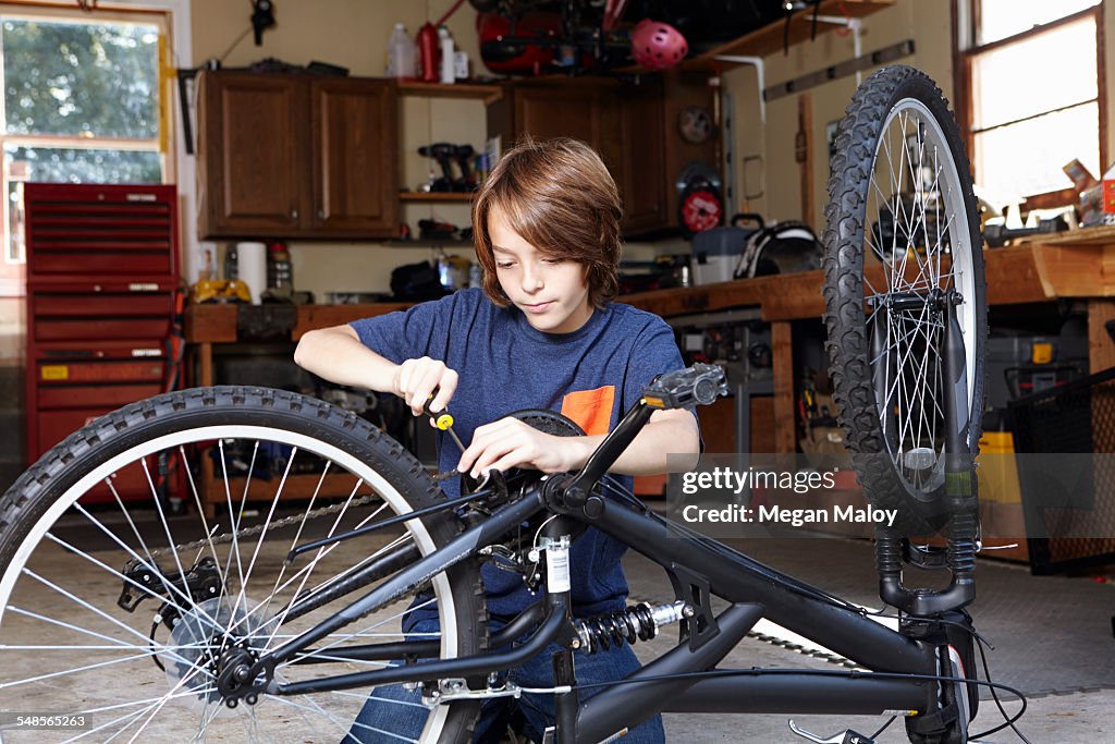 Boy repairing bicycle in garage