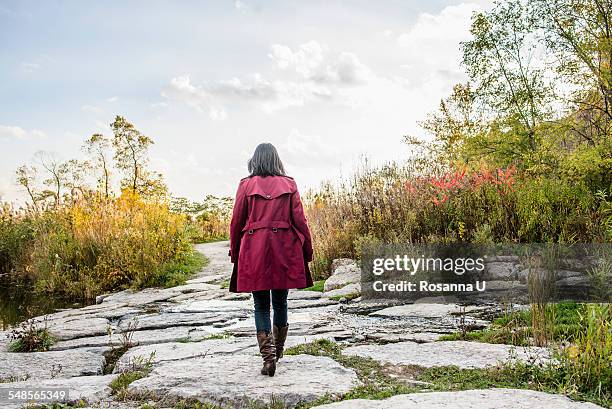 mid adult woman walking on rocks, rear view - coat imagens e fotografias de stock