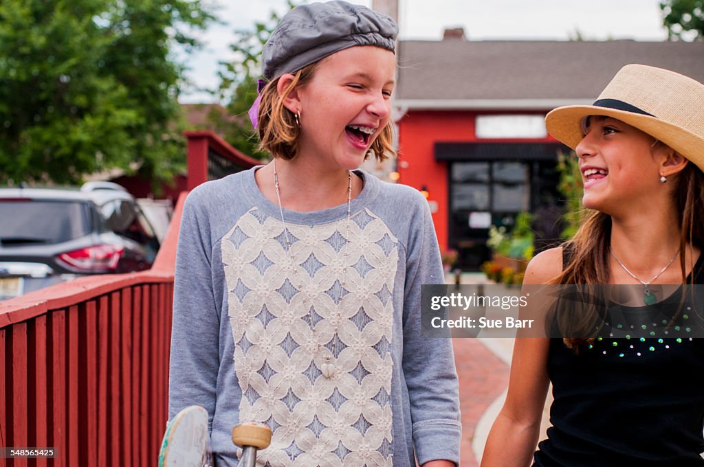 Two girls chatting and laughing whilst walking along street