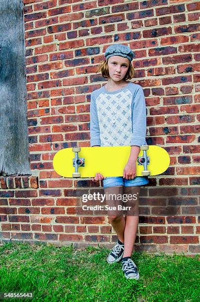 portrait of tomboy skateboarder girl leaning against brick wall - tomboy stockfoto's en -beelden