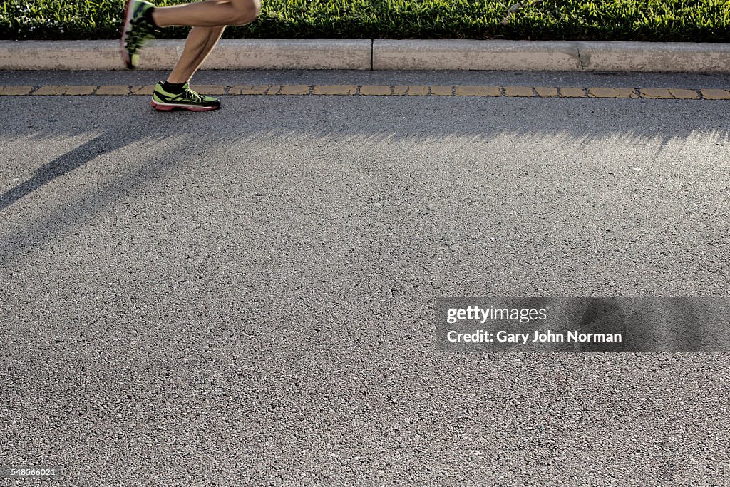 Legs of mature male runner on road run