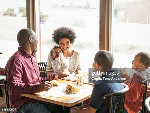 family dining at fast food restaurant - girls laughing eating sandwich foto e immagini stock