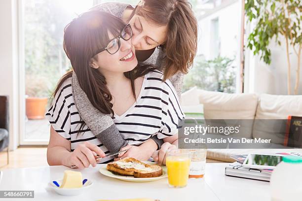 woman kisses girlfriend eating breakfast. - fat lesbian stock pictures, royalty-free photos & images