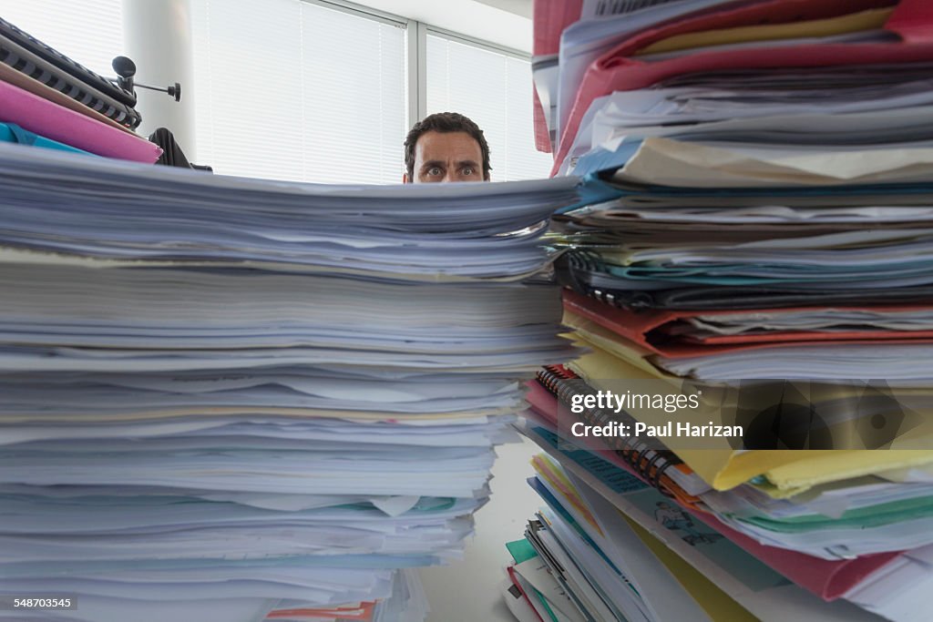 Man surrounded by piles of files in office