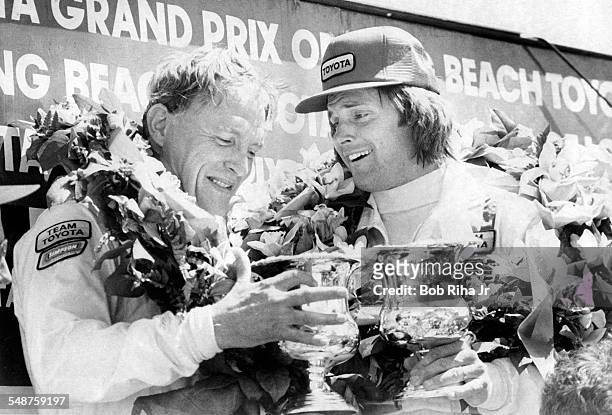 American race car driver Dan Gurney and former professional athlete Bruce Jenner pose together in the Winner's Circle with at the 1982 Toyota...