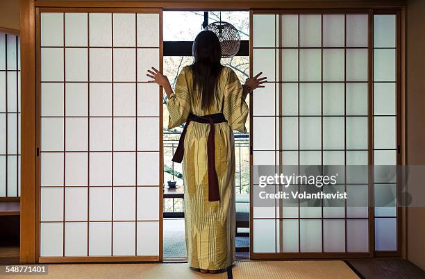 woman wearing a kimono and looking outside japan - obi sash fotografías e imágenes de stock