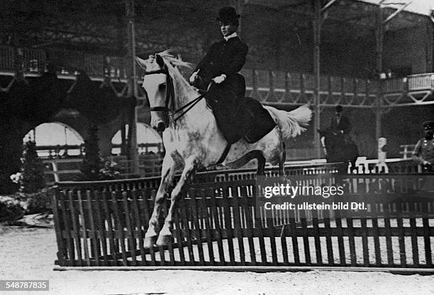 Exhibition hall of the zoological garden Berlin: female jockey in a showjumping competition jumping over a hazard - 1901 - Photographer: Franz Kuehn...