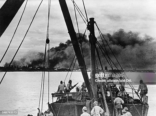 World War II in the Dutch East Indies Japanese troops landing on Sumatra; at the back burning oil tanks - 1942 - Vintage property of ullstein bild