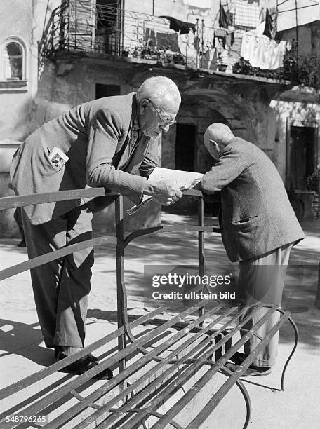 Frankreich: zwei alte Maenner lesen Zeitung, gestuetzt auf eine Bank stehend - 1960 Foto: Siegfried Lauterwasser