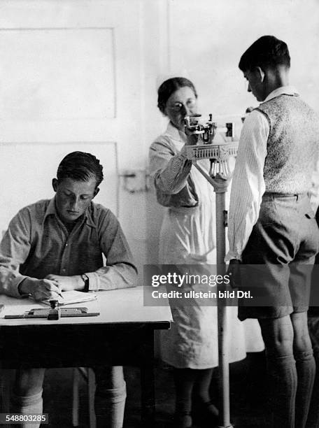 Germany : pupils of a South German school, a boy is weighed at a medical school examination - 1933 - Photographer: Kurt Huebschmann - Vintage...