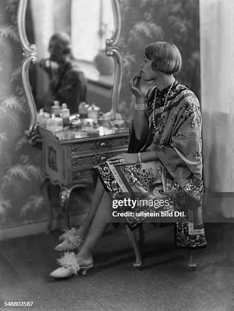 Heel, Ellen - Actress - full-figure portrait - Series: From morning until midnight, in kimono dressing gown, putting on lipstick - 1925 -...