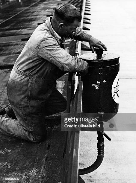 Car mechanic working on a tank, placed on the roof - about 1930 - Photographer: Heinz von Perkhammer Vintage property of ullstein bild