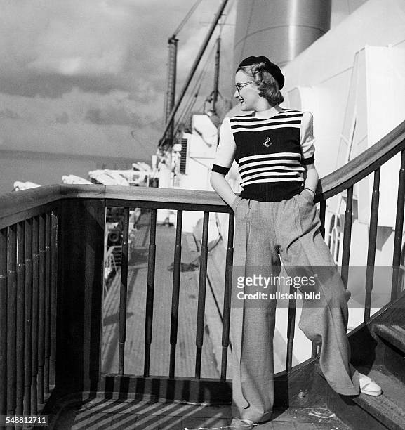 Fashion on deck of the 'Bremen Europe': woman in a dark blue pullover with white stripes and a grey flannel pant - 1939 - Photographer: Karl Ludwig...
