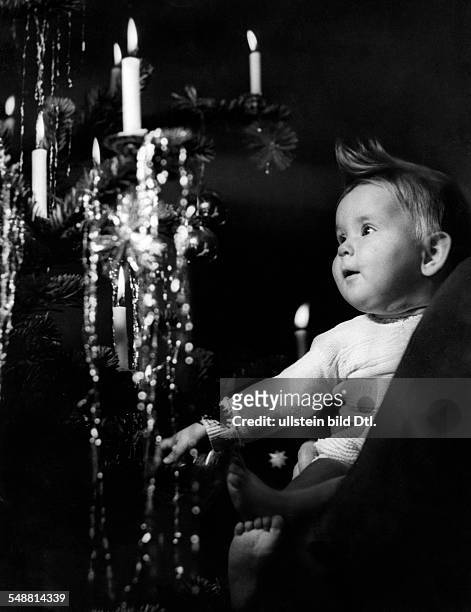 Christmas: A Baby looking at the incandescent Christmas tree - 1935 - Photographer: Hedda Walther Vintage property of ullstein bild