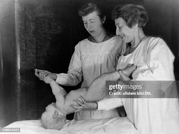 Medicine, people: nurse doing gymnastics with a baby - 1927 - Photographer: Suse Byk - Published by: 'Berliner Morgenpost' Vintage property of...