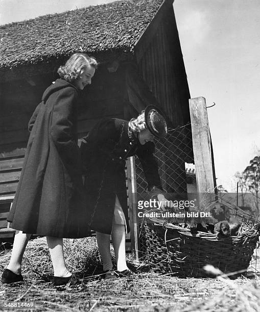 Mode: two women in long coats, the coat on the trimmed with piping, the coat on the left, with far back part and hood model: Ski Hut - 1940 -...