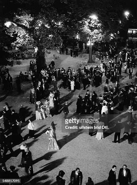 France; Paris: race-course Longchamp, people in evening dresses in a lighted garden - 1936 - Photographer: Gyula H. Brassai - Published by: 'Die...